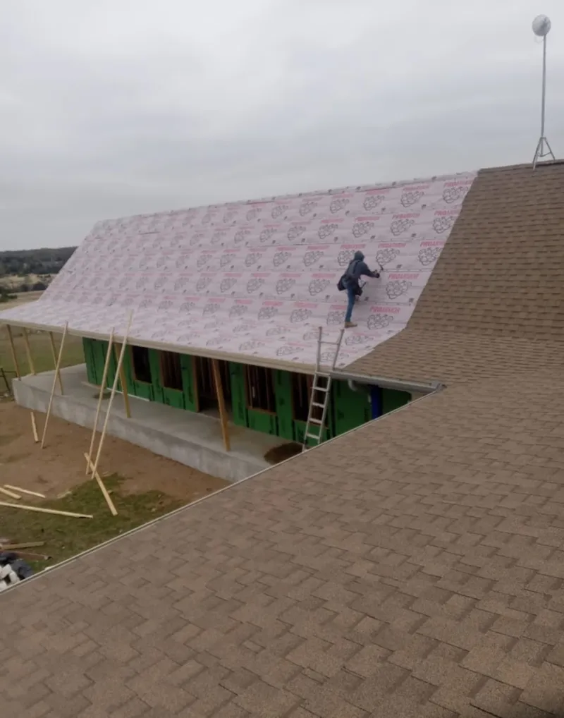 Worker preparing underlayment for a metal roof installation in Gun Barrel City